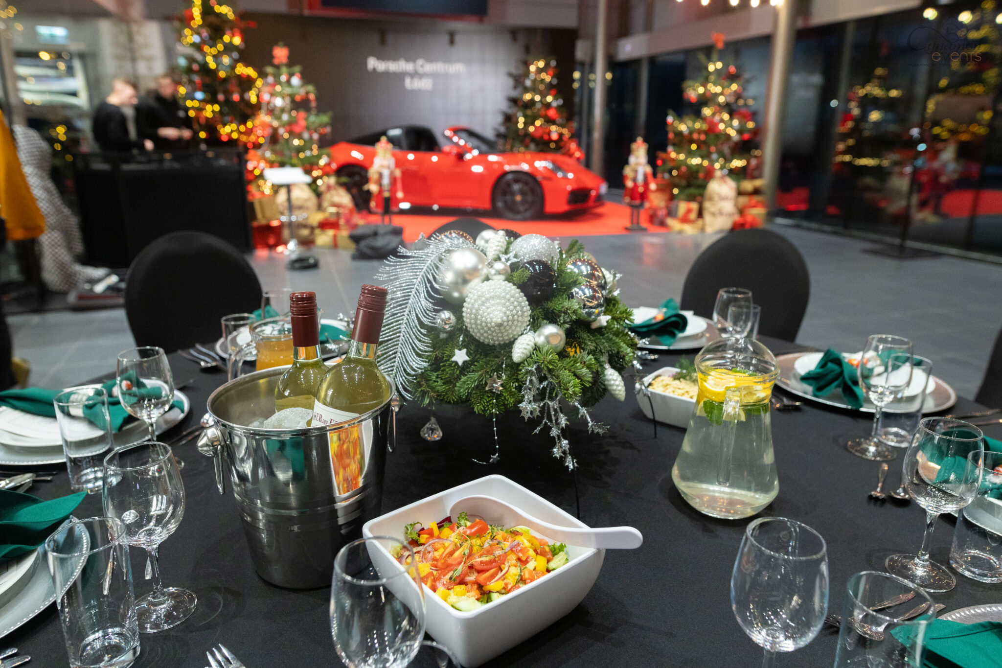 Goście przy elegancko udekorowanych stołach podczas świątecznego eventu firmowego w salonie Porsche – obsługa cateringowa Cynamon Events.