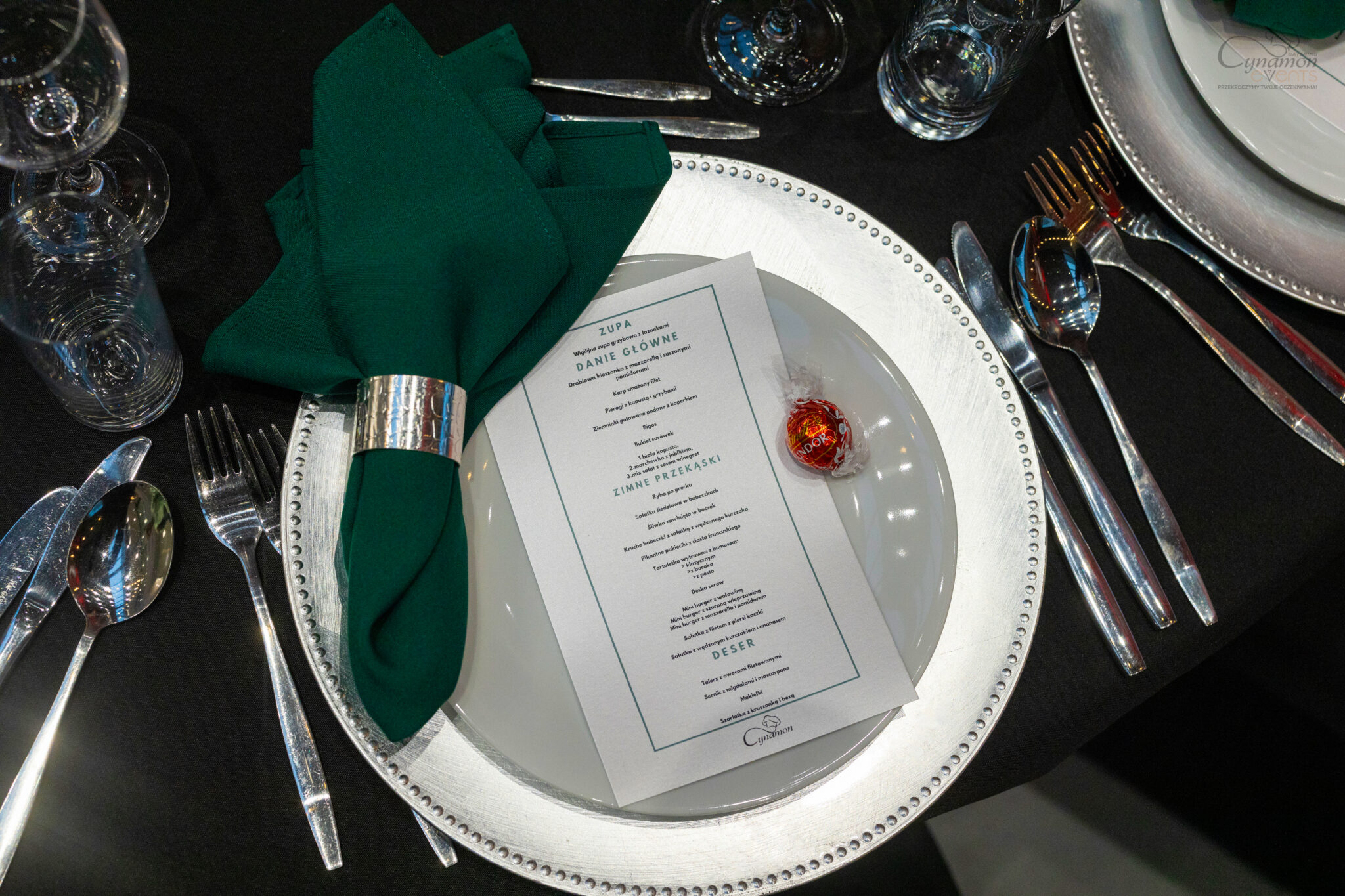 Eleganckie nakrycie stołu z zieloną serwetą, winietką i menu – catering eventowy klasy premium.